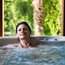 Donna rilassata in vasca idromassaggio con sfondo naturale verde
